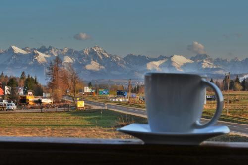 a coffee cup sitting on a window sill with a view of mountains at Dom Wypoczynkowy Skorusa in Białka Tatrzanska