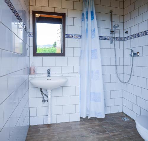 a white bathroom with a sink and a window at Máli Pince in Aszófő