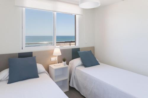two beds in a bedroom with a view of the ocean at AG Aquarium in Playa de Gandia