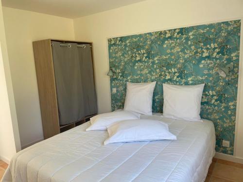 uma cama com duas almofadas e uma parede floral em Gîte Les Mimosas - 2 à 4 personnes - Vue imprenable em Largentière