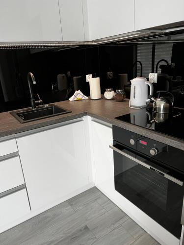 a kitchen with white cabinets and a sink and a stove at Apartment Comfort in Bartoszyce