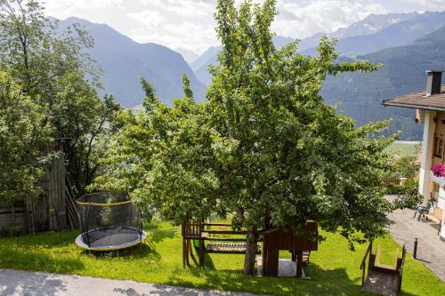ein Haus mit einem Baum und einer Schaukel in der Unterkunft Ferienwohnungen Zinzlerbauer in Uttendorf