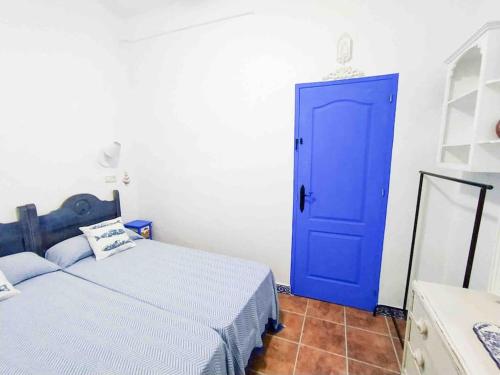 Una puerta azul en una habitación blanca con cama en “Flor de Sal” Charming Traditional Andalusian House, en Ayamonte