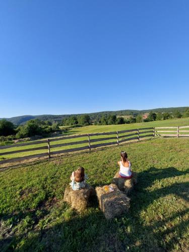 two women sitting on rocks in a field at Planinska kuća Isiteo in Kremna