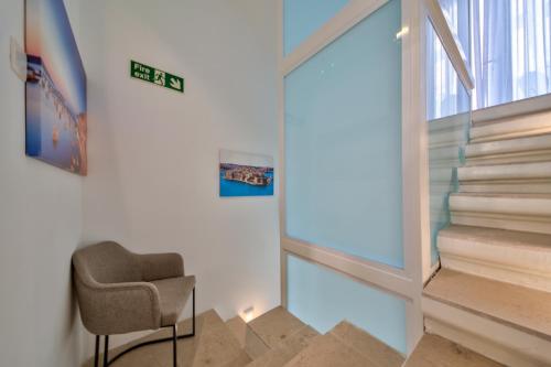 a stairway with a chair and a glass wall at Tritoni Mini Studios - Valletta in Il-Furjana