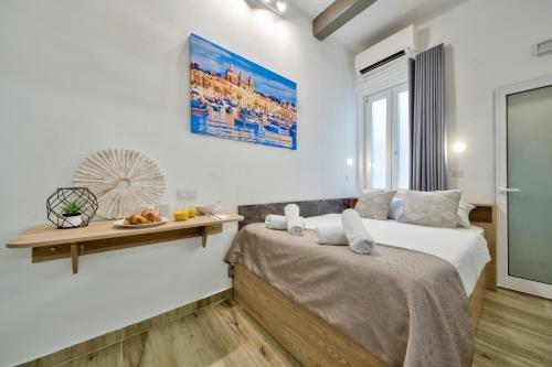 ein weißes Schlafzimmer mit 2 Betten und einem Tisch in der Unterkunft Tritoni Mini Studios - Valletta in Floriana