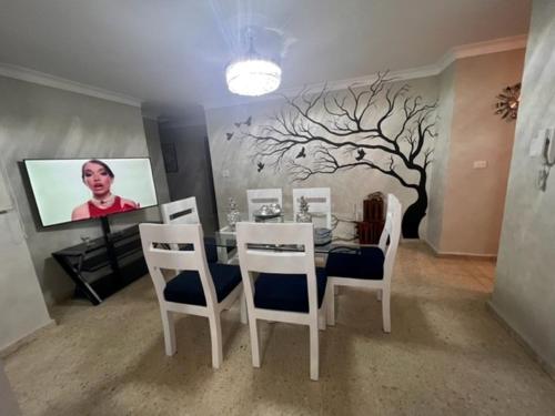 a dining room with a table and a tree on the wall at madrigal 1-3br with parking in Santiago de los Caballeros