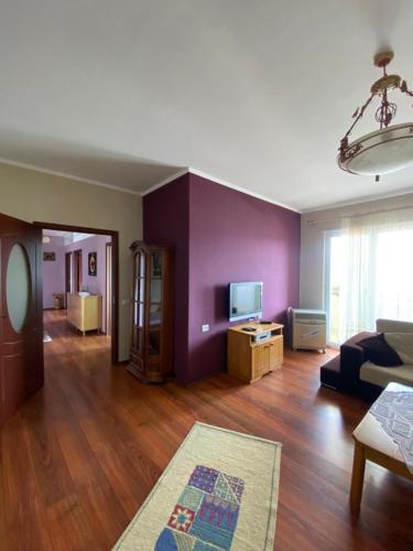 - un salon avec des murs violets et un canapé dans l'établissement Stay the Night Shkodra Apartment City Centre, à Shkodër