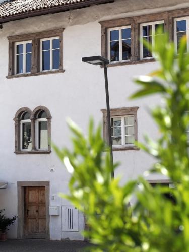 a white house with windows and a street light at Marktplatz 10 in Caldaro