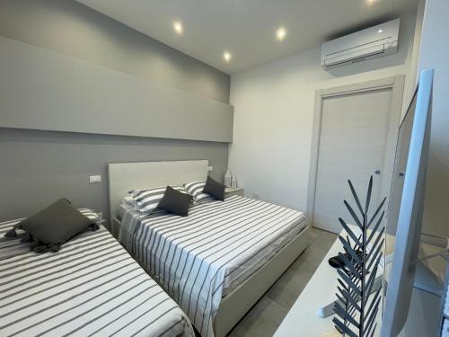 two beds in a bedroom with white walls at Appartamento Albachiara Vistamare in Cesenatico