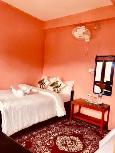a bedroom with two beds and a table with a mirror at Shristi Hotel & Lodge in Bandīpur