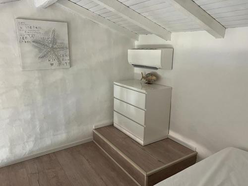 una camera bianca con cassettiera e una foto sul muro di Residence Ginepro, appartamento Baia Caddinas a Golfo Aranci