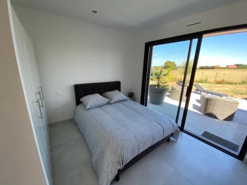 een slaapkamer met een bed en een glazen schuifdeur bij La Pousada in Peuplingues