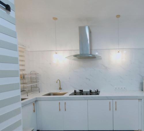 a white kitchen with a sink and a stove at Spring Fields Homestay by Sizma in Semenyih