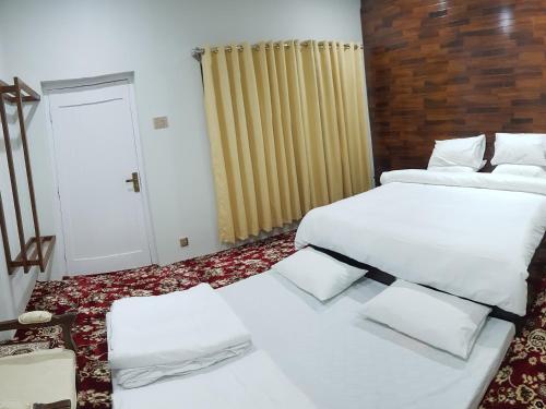 a room with two beds and a door with a window at Ehsan-e-Bassi in Gilgit