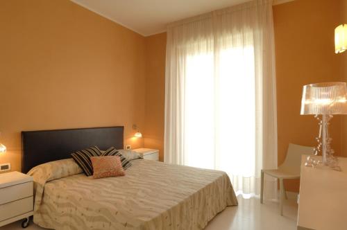 a bedroom with a bed and a large window at Residence Oliveto in Ceriale