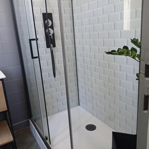 une douche avec une porte vitrée dans une salle de bain dans l'établissement Agréable maison de village à coté de la DOLCE VIA, à Saint-Sauveur-de-Montagut