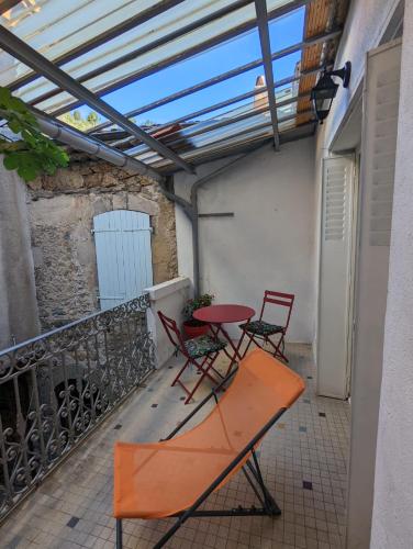 een patio met een tafel en stoelen op een balkon bij Agréable maison de village à coté de la DOLCE VIA in Saint-Sauveur-de-Montagut