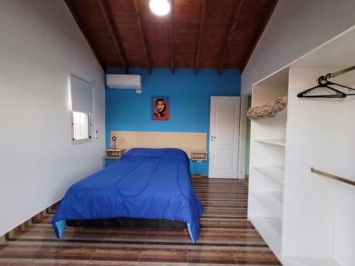 Cama en habitación con pared azul en Cabañas San Pío en Merlo