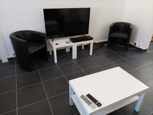 sala de estar con 2 sillas negras y TV en O'Couvent - Appartement 97 m2 - 4 chambres - A514 en Salins-les-Bains