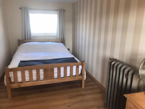 a bedroom with a bed and a window and a radiator at Honey lodge in Caeathro