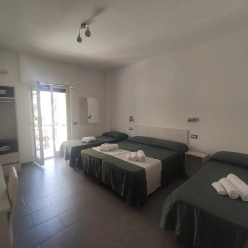 a bedroom with two beds and a door to a patio at Ninfea Tropea City Rooms in Tropea