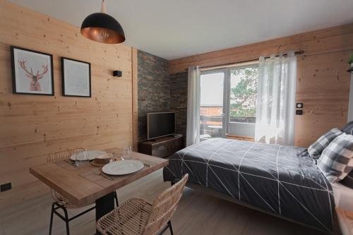 een slaapkamer met een bed, een tafel en een televisie bij Alt 985M - Appartement de Charme au Grand-Bornand in Le Grand-Bornand