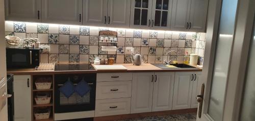 a kitchen with white cabinets and tiles on the wall at Vinný sklep a penzion U Bobule in Louka