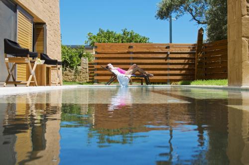 a woman sitting on a bench next to a pool of water at Conte Marino Villas in Maleme