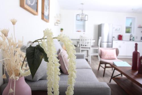 a living room with a gray couch with white flowers at Gateway to Greenwich Suites in Saint Peters