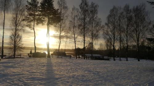 a snow covered park with the sun setting behind trees at SELMENT RESORT Mazury in Ełk
