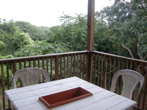 a wooden deck with a white table and two chairs at Apartments Chez Milady in Utila