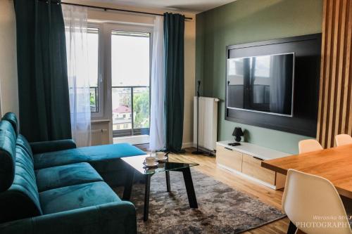 a living room with a blue couch and a large window at D Apartments Centrum Prowiantowa II in Białystok