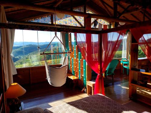 a bedroom with a hammock in a room with a view at Chalés Grande Vista - Difícil não se maravilhar! in Cunha