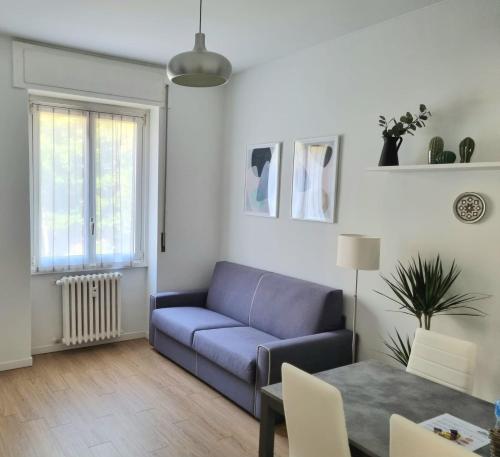 ein Wohnzimmer mit einem blauen Sofa und einem Tisch in der Unterkunft Claro Apartments - Prampolini 12 in Mailand