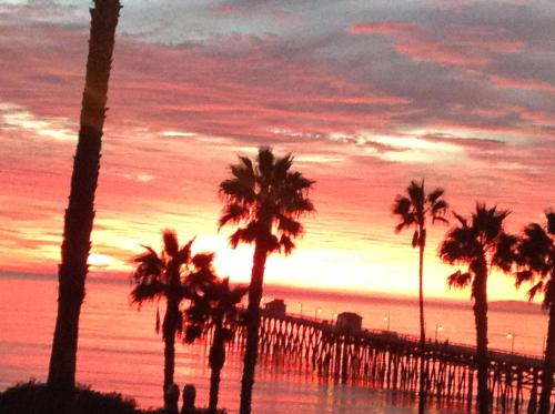 a sunset at the beach with palm trees and a pier at Sea Horse Resort in San Clemente