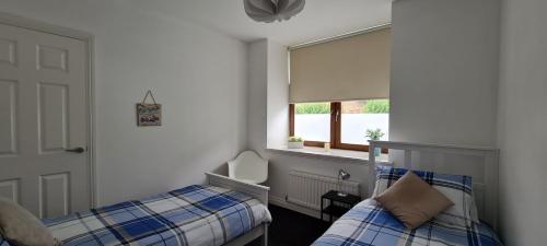 a bedroom with two twin beds and a window at The Heathers - near beach & free golf bag & clubs. in Maybole