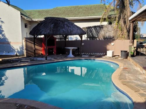 a swimming pool with an umbrella next to a house at Othandweni Holiday Home in Durban