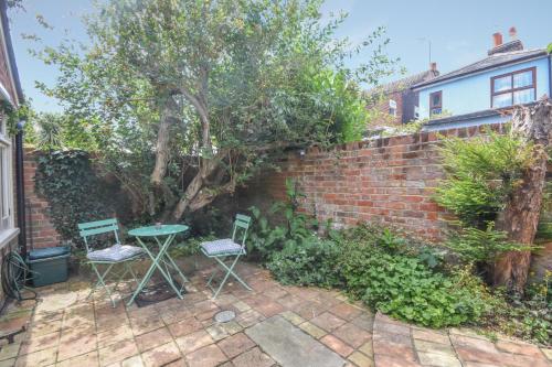 a patio with a table and chairs next to a brick wall at Unique period one bedroom house in Colchester in Colchester