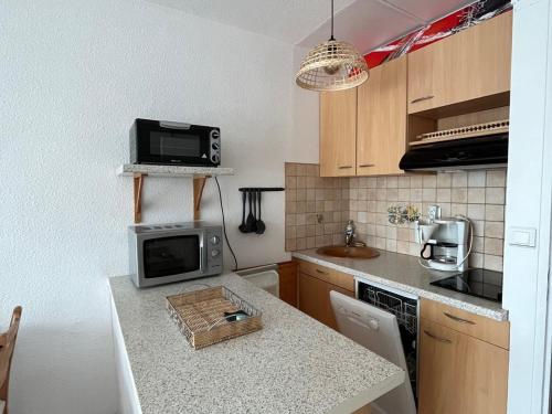 une cuisine avec une table et un four micro-ondes. dans l'établissement Studio cabine à Villard-de-Lans, pour 4 pers, parking gratuit - FR-1-515-139, à Villard-de-Lans
