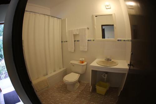 a white bathroom with a toilet and a sink at Moonrisevillas in Negril