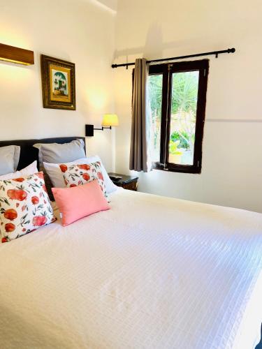 a bedroom with a white bed with a pink pillow at Finca Sa Canova Agroturismo in Campos