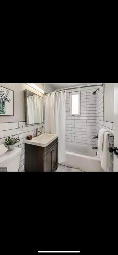ein weißes Badezimmer mit einer Badewanne, einem Waschbecken und einer Badewanne in der Unterkunft Lovely 1-bedroom rental unit with free parking in Washington