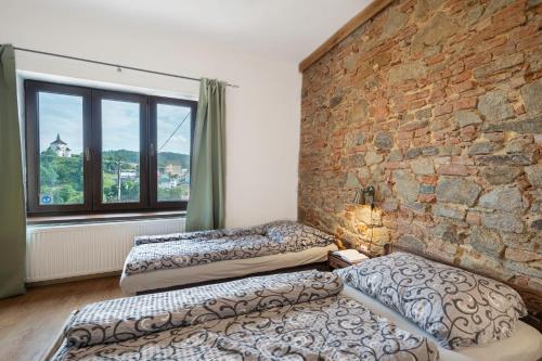 two beds in a room with a brick wall at Apartman Belavita in Banská Štiavnica