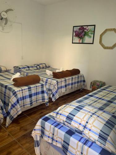 a room with three beds in a room with a fan at FAMÍLIA CHARLEAUX in Aparecida