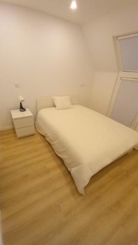 um quarto com uma cama branca e piso em madeira em Casa Aveiro Modern House em Aveiro