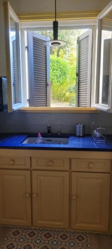 un comptoir de cuisine avec un évier et une fenêtre dans l'établissement Un havre de paix proche du centre et des plages grand appartement avec un canape lit et un coin nuit lit double, à Cavalaire-sur-Mer