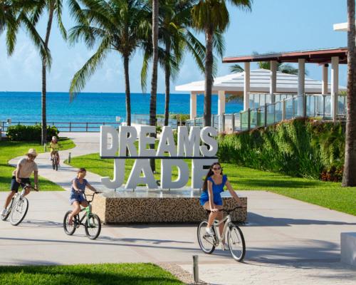 La gente montando bicicletas delante de un cartel que lee sueños jabba en Dreams Jade Resort & Spa - All Inclusive, en Puerto Morelos