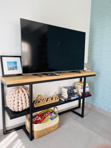 a flat screen tv on a table with a shelf at Kustverhuur, Park Schoneveld, Zeester 63 in Breskens