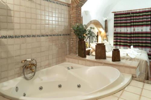 La salle de bains est pourvue d'une grande baignoire blanche et d'un lit. dans l'établissement Cuevas Pedro Antonio de Alarcon, à Guadix